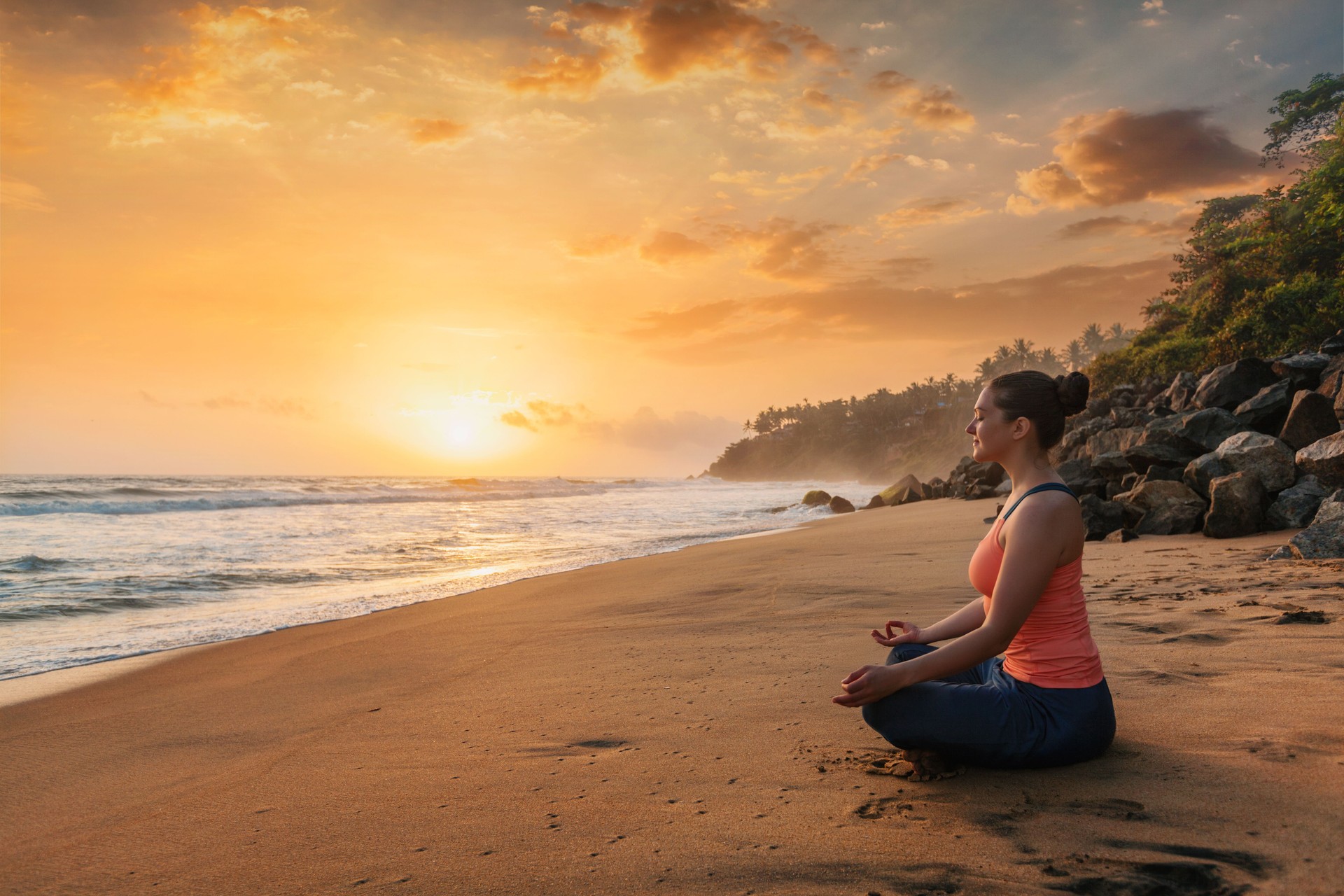 Woman doing yoga at beach - Padmasana lotus pose